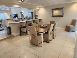 A dining area with a wooden table and chairs, a kitchen in the background, and a large mirror on the wall. - 3-bedroom house in peaceful Naples Inn & Docks (Naples)
