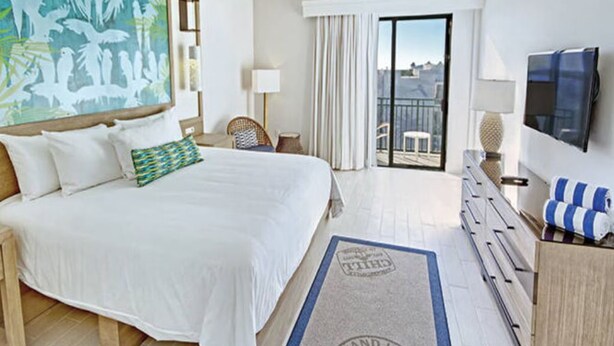 A hotel room with a bed, a TV, a balcony with a view, and a painting on the wall. - Studio Deluxe, Ocean View, at Wyndham Rio Mar in Puerto Rico, on Golf Course! (Río Grande)