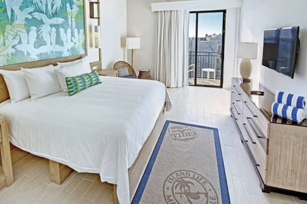 Ein Hotelzimmer mit Bett, Fernseher, einem Balkon mit Blick und einem Gemälde an der Wand.