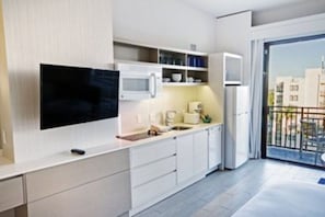 Eine moderne Küche mit Flachbildfernseher, weißen Schränken und integriertem Mikrowellenherd.