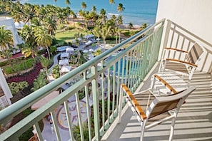 Ein Balkon mit Blick auf einen Ferienort, inklusive Palmen und einem Pool.