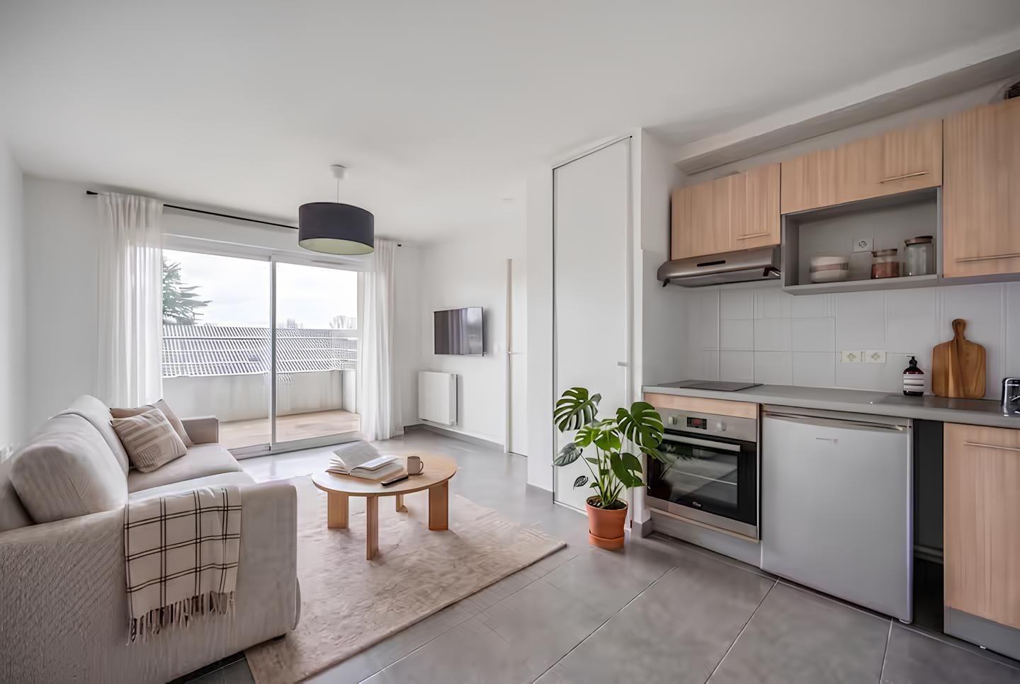 A modern apartment with a living area, kitchen, and a balcony with a view.