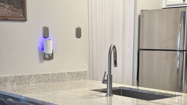 Una cocina con encimera de granito, electrodomésticos de acero inoxidable y taburetes de bar.