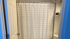 Un baño con cortina de ducha, inodoro y armarios.