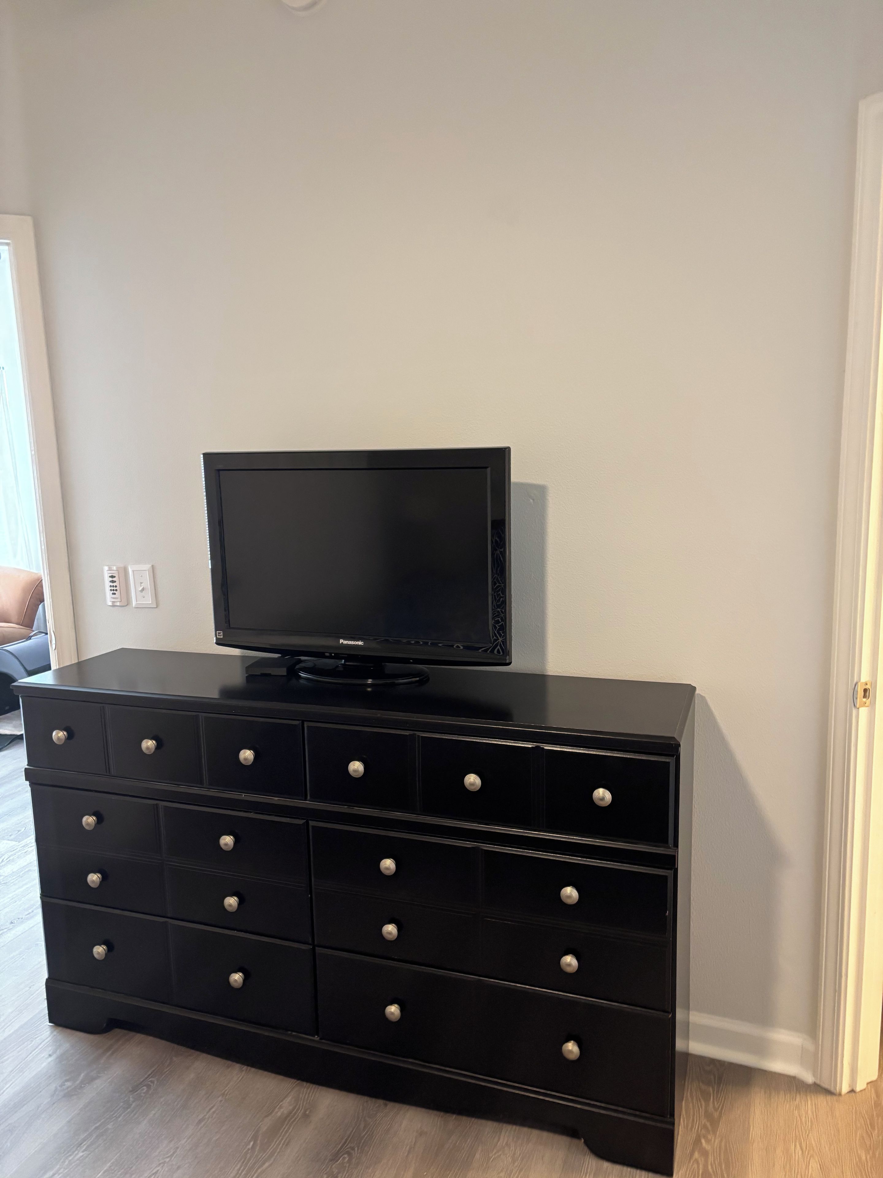 Un mueble multimedia negro con televisor de pantalla plana, varios cajones y un enchufe.