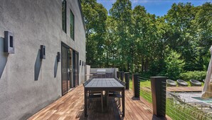 Un patio exterior con terraza de madera, una parrilla y una zona de estar.