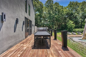 Eine Terrasse im Freien mit Holzdeck, Grill und Sitzgelegenheit.