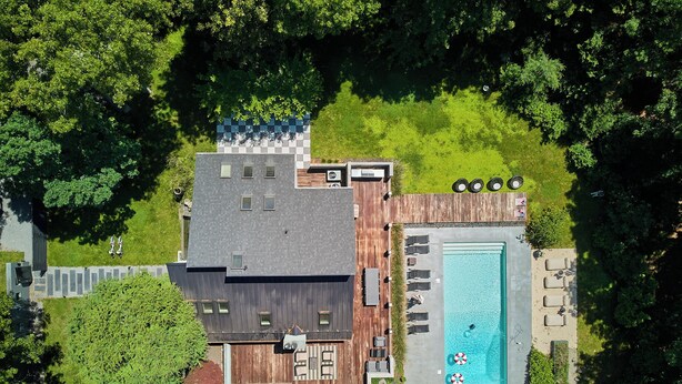 Una casa moderna con piscina, mobiliario exterior y patio cercado.