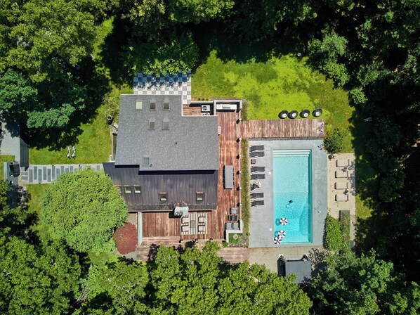 Ein modernes Haus mit Schwimmbad, Sitzgelegenheiten im Freien und einem eingezäunten Garten.