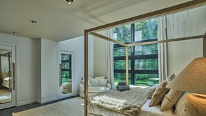 Un dormitorio con cama con dosel, un ventanal y vistas a la vegetación.