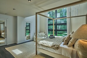 Ein Schlafzimmer mit Himmelbett, großem Fenster und Blick ins Grüne.