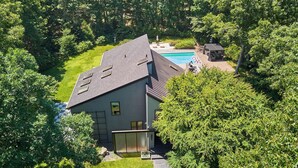 Una casa moderna con piscina, rodeada de abundante vegetación.