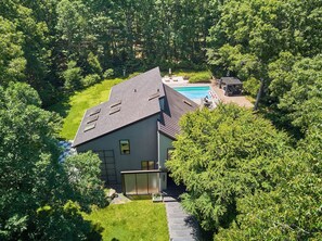 Ein modernes Haus mit Swimmingpool, umgeben von üppiger Vegetation.