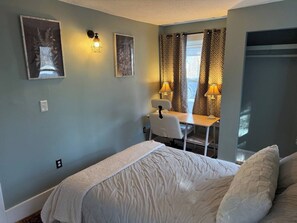 A bedroom with a bed, a desk, and two wall-mounted lamps.