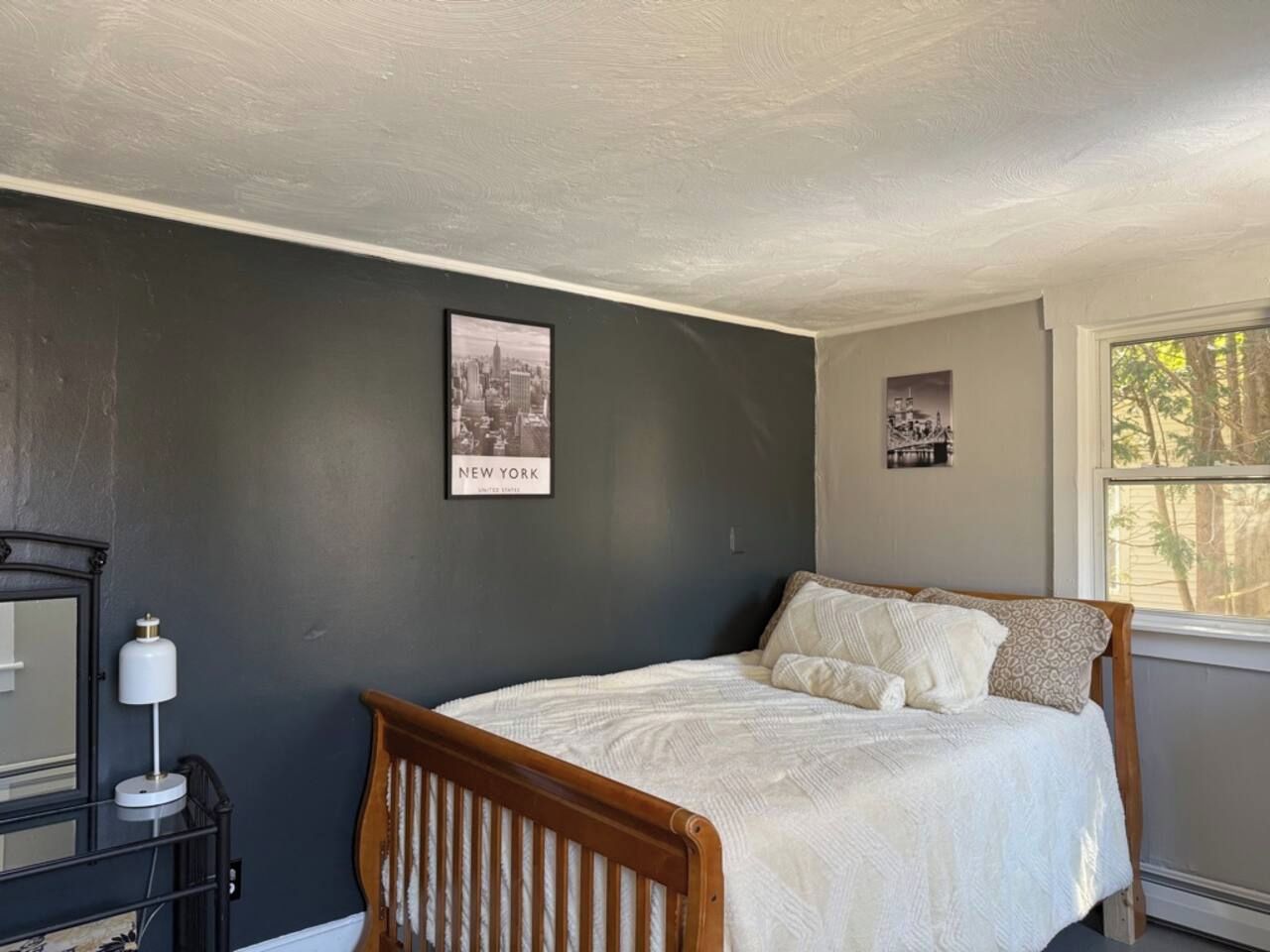 A bedroom with a bed, a nightstand, a lamp, and a framed picture on the wall.