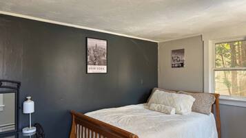 A bedroom with a bed, a nightstand, a lamp, and a framed picture on the wall.