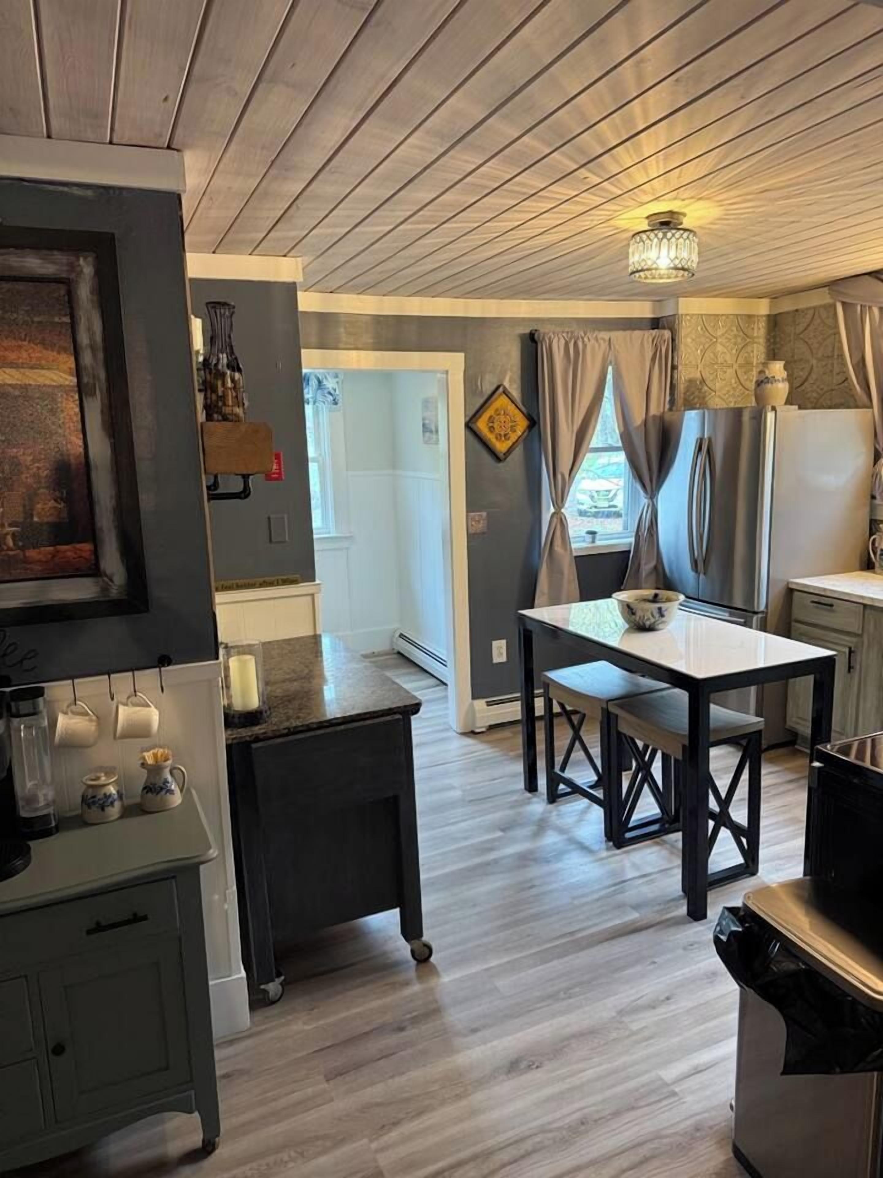 A kitchen with a dining table, a refrigerator, and a coffee machine.