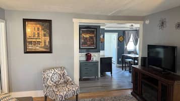 A living room with a patterned armchair, a television, and a coffee maker on a small table.
