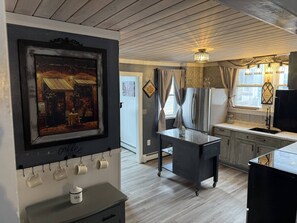 A kitchen with a coffee station, a dining area with a table, and a view of the outside.