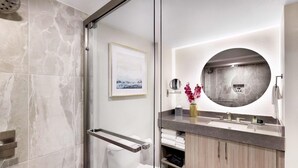 Ein modernes Badezimmer mit Duschkabine aus Glas, Toilette, Waschbecken mit Waschtisch und einem großen Spiegel.