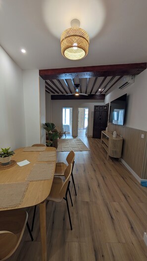 A dining area with a wooden table and chairs, a hanging light fixture, and a view into the kitchen. - Renovated Apartment with Air Conditioning - Just Steps from the Beach (Alicante (Alacant))