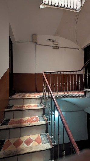 A staircase with a handrail, a wall-mounted light fixture, and a tiled floor with a geometric pattern. - Renovated Apartment with Air Conditioning - Just Steps from the Beach (Alicante (Alacant))