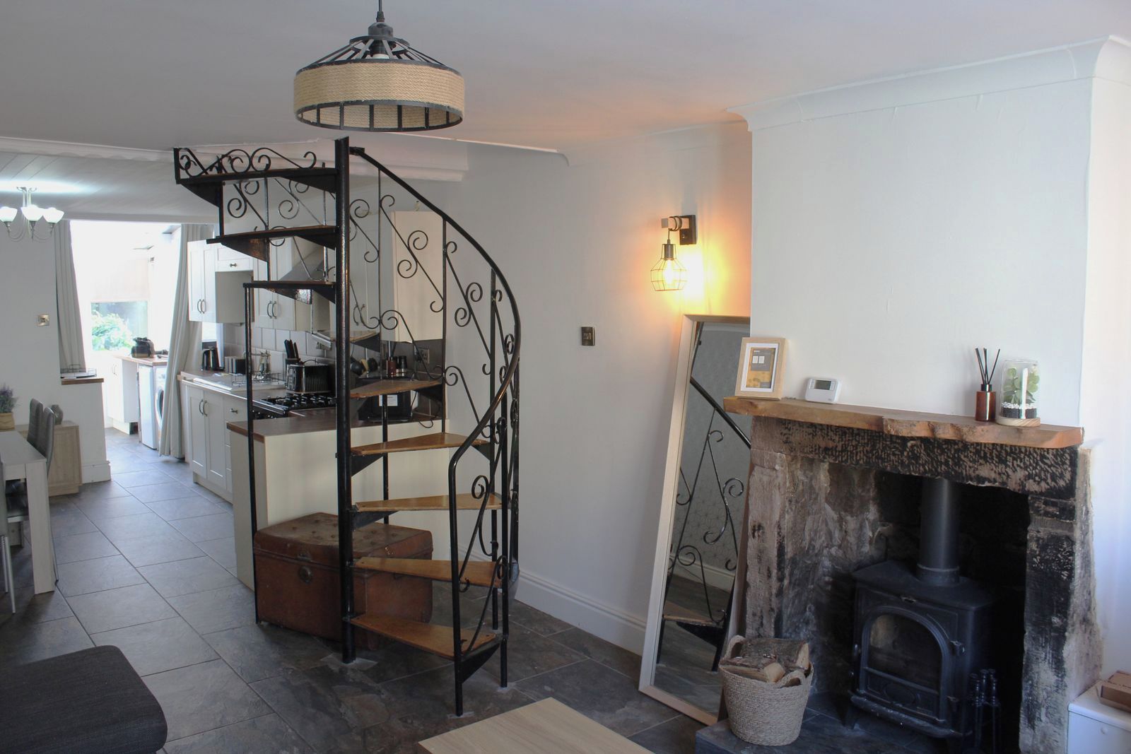 A kitchen with a spiral staircase, a fireplace, and a dining area with a view of the outside.