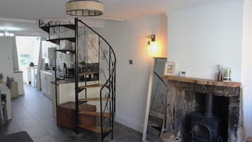 A kitchen with a spiral staircase, a fireplace, and a dining area with a view of the outside.