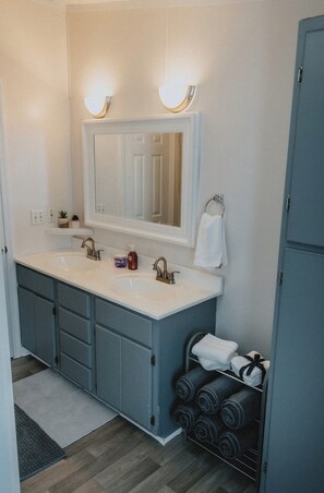 A bathroom with two sinks, a mirror, and a towel rack.