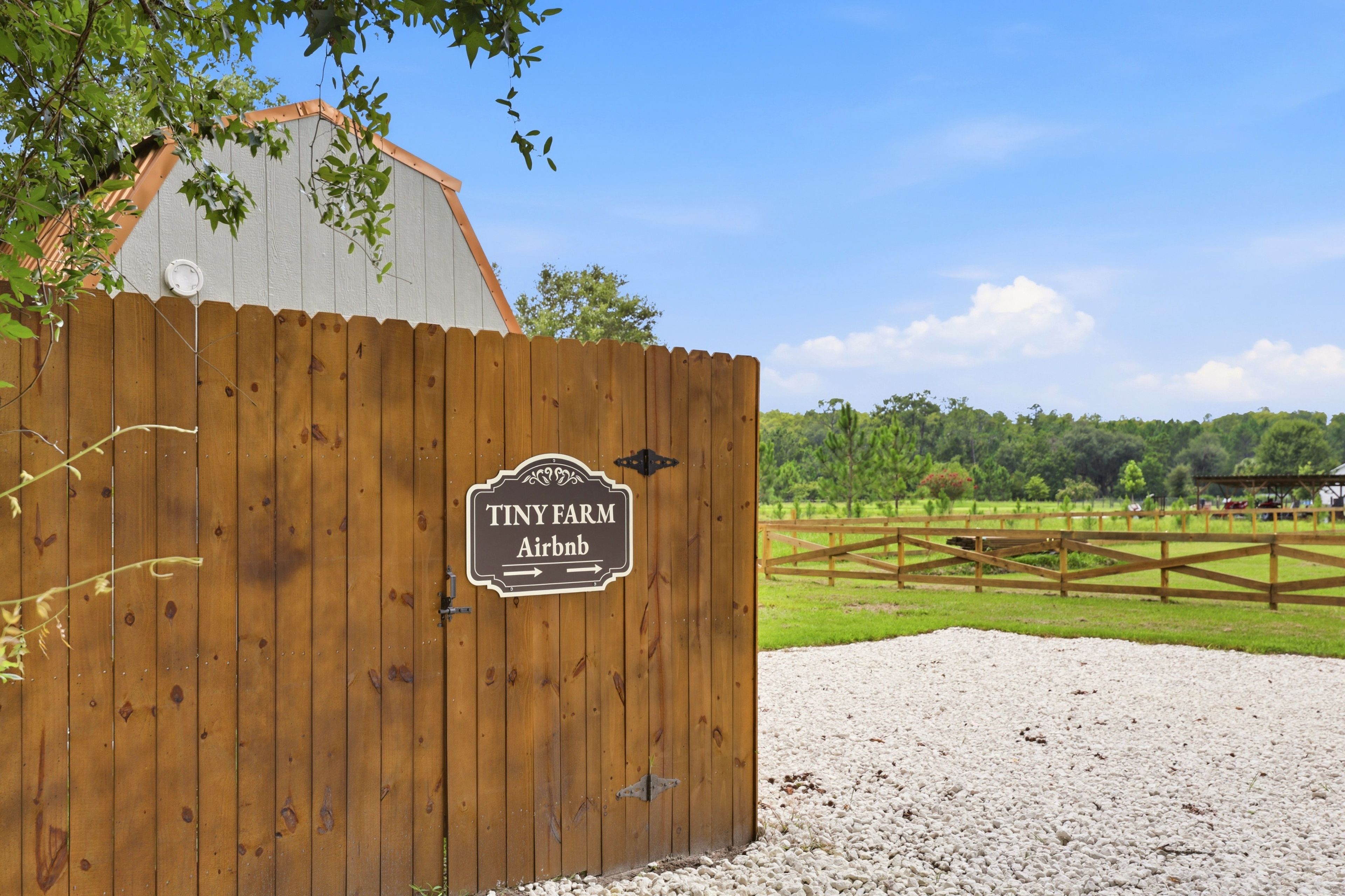 Een houten poort met een bord waarop staat 'Tiny Farm Airbnb'.