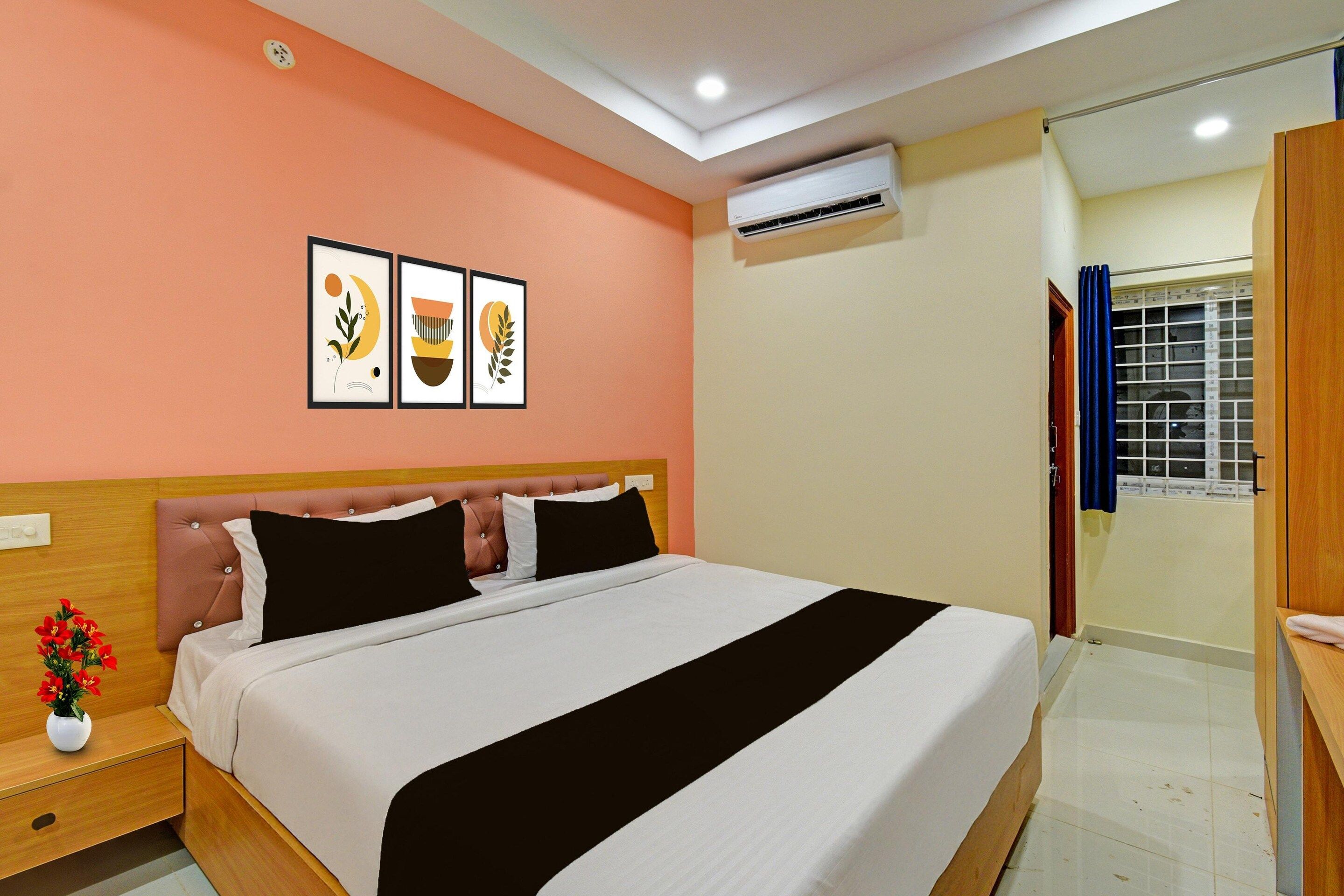 A hotel room with a bed, a nightstand, a wall-mounted air conditioner, and a window with curtains.