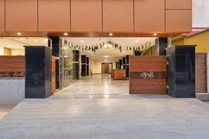 A hotel lobby with a marble floor, wooden reception desk, and glass doors. - Classic Gachibowli Bus Terminal (Hyderabad)