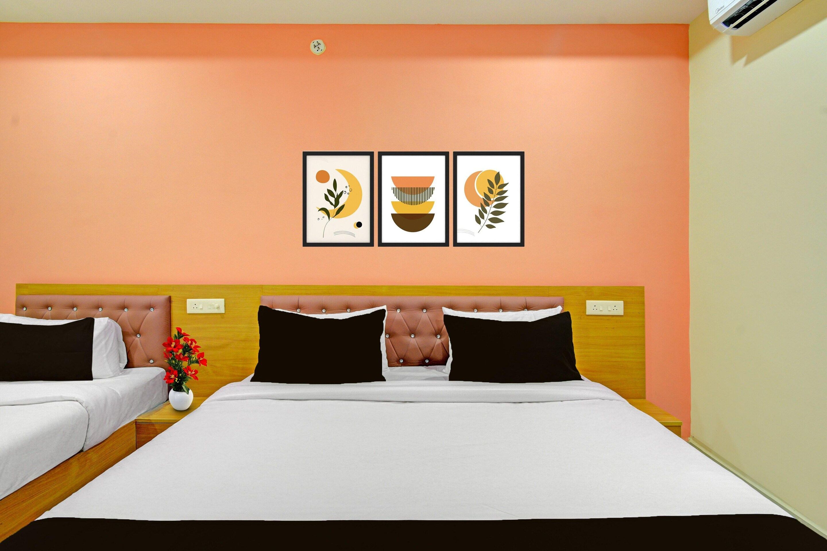 A hotel room with a large bed, two bedside tables, a vase with flowers, and three framed artworks on the wall.