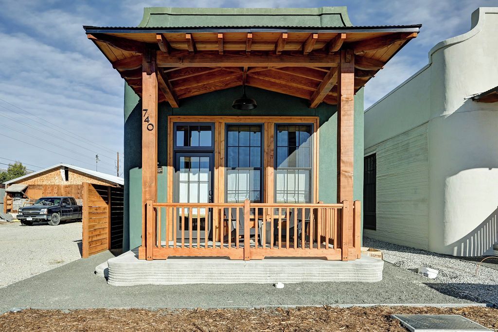 A small building with a porch, wooden beams, and a garage door.