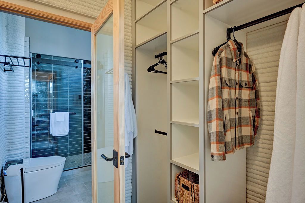 A bathroom with a toilet, a glass shower enclosure, and a white towel hanging on the wall.
