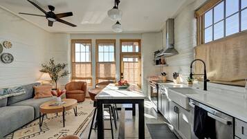 A modern kitchen with a central island, a dining area with a sofa and chairs, and a ceiling fan.