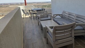 En balkong med ett bord och stolar, en soffa och utsikt över stadsbilden.