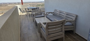 Een balkon met een tafel en stoelen, een bank en uitzicht op de stad.