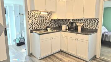 A modern kitchen with white cabinets, a black and white backsplash, and a coffee maker.