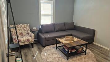 A living room with a sofa, a chair, a coffee table, and a lamp.