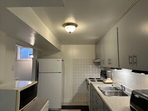 A compact kitchen with a refrigerator, microwave, stove, and sink. - Central Oakville/Kerr Village:steps to shops, eateries, cinema, transit, & GO  (Oakville)