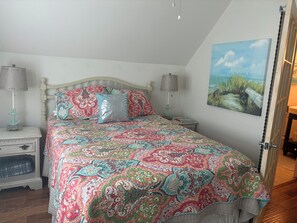 A bedroom with a bed, two nightstands, a lamp, a painting, and a door. - Fabulous 3-bedroom house with AC in Panama City Beach (Panama City Beach)