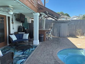 Um quintal com piscina, móveis de pátio e área de estar coberta.