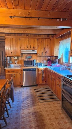 A kitchen with wooden cabinets, a microwave, a toaster, a sink, and a dishwasher. - Cozy 3 bedroom with loft cabin in serene Pittsburg with AC & woodstove. (Pittsburg)