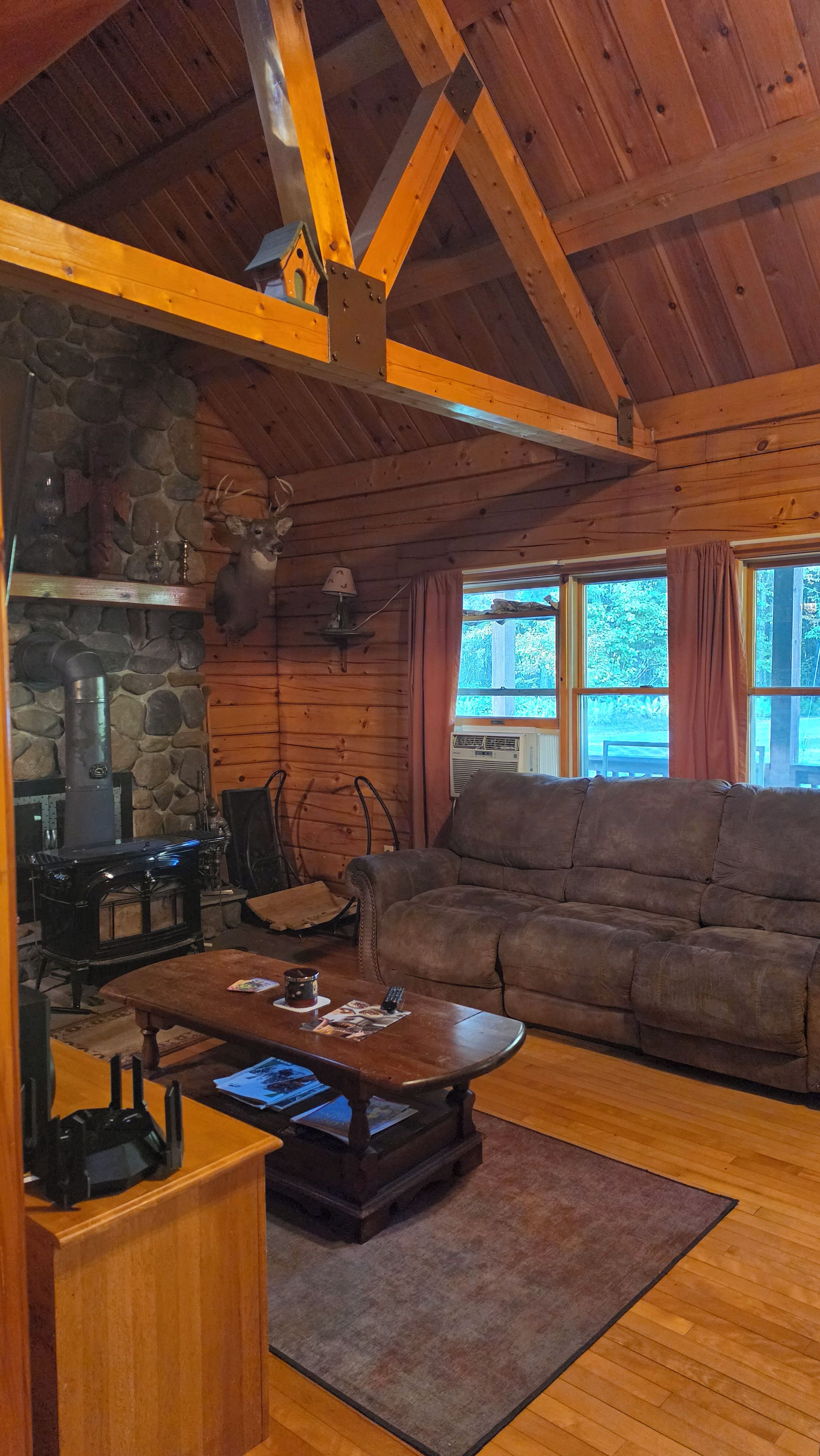 A cozy cabin interior with a stone fireplace, a sofa, and a coffee table.