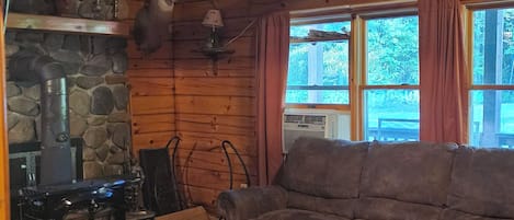 A cozy cabin interior with a stone fireplace, a sofa, and a coffee table.