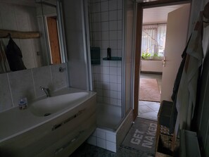 A bathroom with a white sink, mirror, and tiled walls. - Cozy little bungalow with a fireplace and pool in a quiet location—5 minutes from the F60 (Heideland)