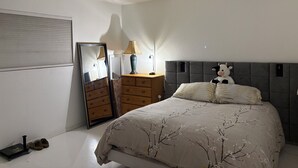 Een slaapkamer met een bed, een kaptafel, een spiegel, een lamp en een knuffel.