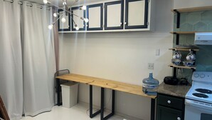 Een kleine keuken met een inbouwfornuis, een waterdispenser en een houten tafel.