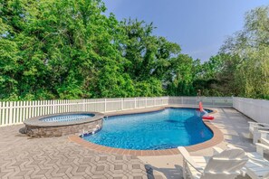 A swimming pool with a stone surround, a white picket fence, and a patio area with lounge chairs. - Cape Mayzing! Pool, Sleeps 12, West Cape May (West Cape May)